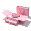 Pink gift drawer box with drawer open and white shredded paper